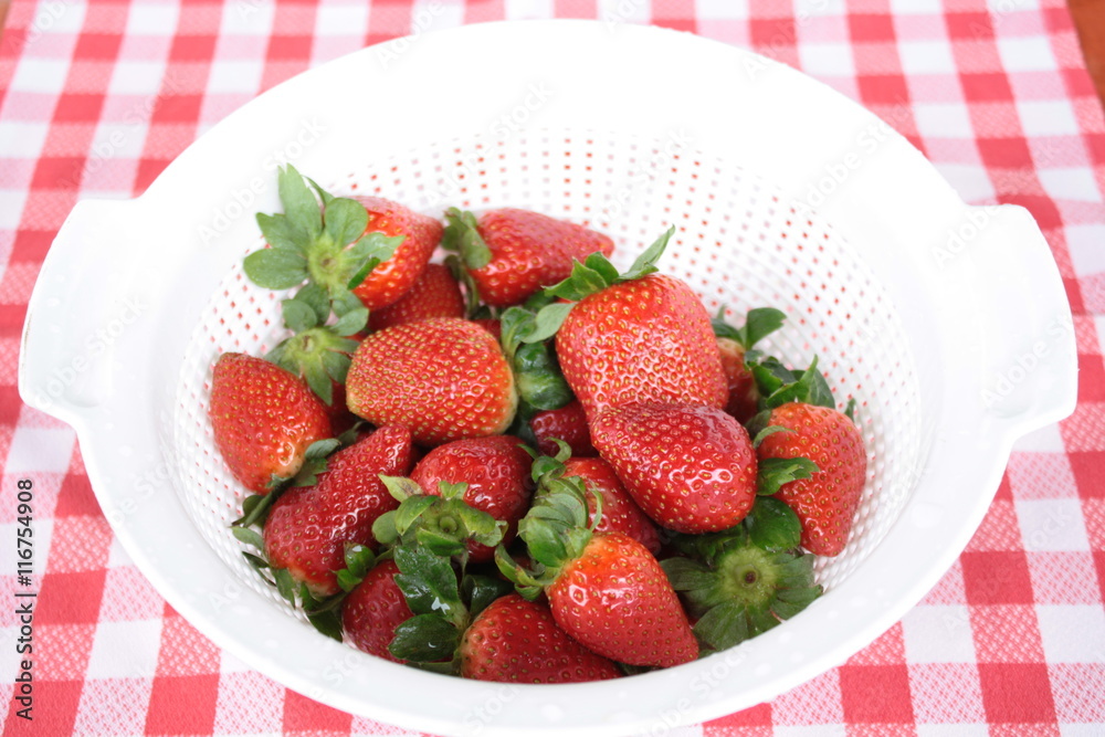 Close-up view of washed strawberries reflecting in a white pot Close-up view of washed strawberries reflecting in a white pot