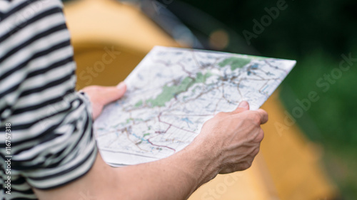 Tourist reading geographic map choosing best way. Adventure in wild nature, active lifestyle