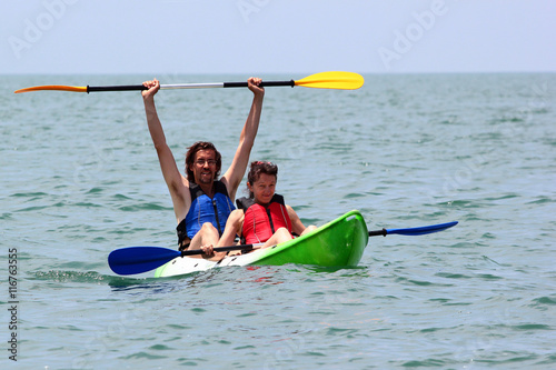 Couple of kayakers rowing in sea water