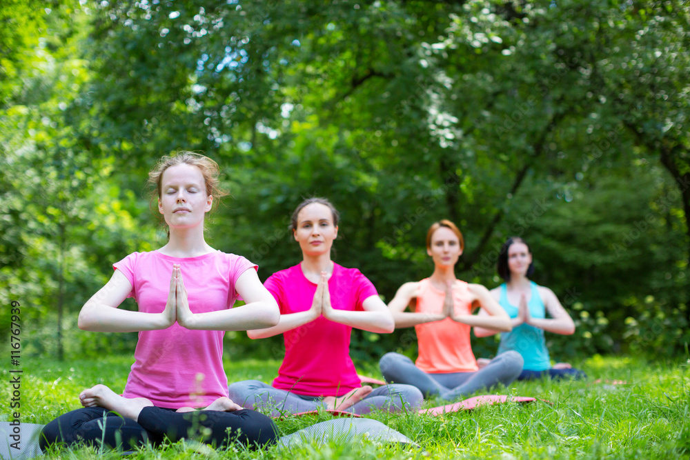 Fitness group doing yoga in park.