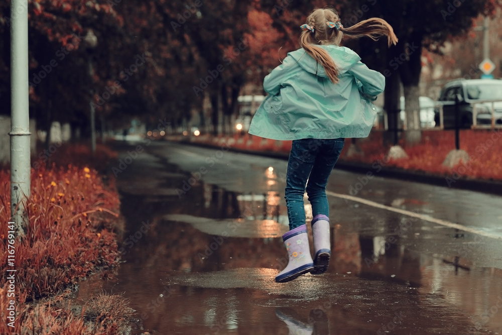 girl jumping in the puddles in the autumn rain girl jumping in the puddles in the autumn rain