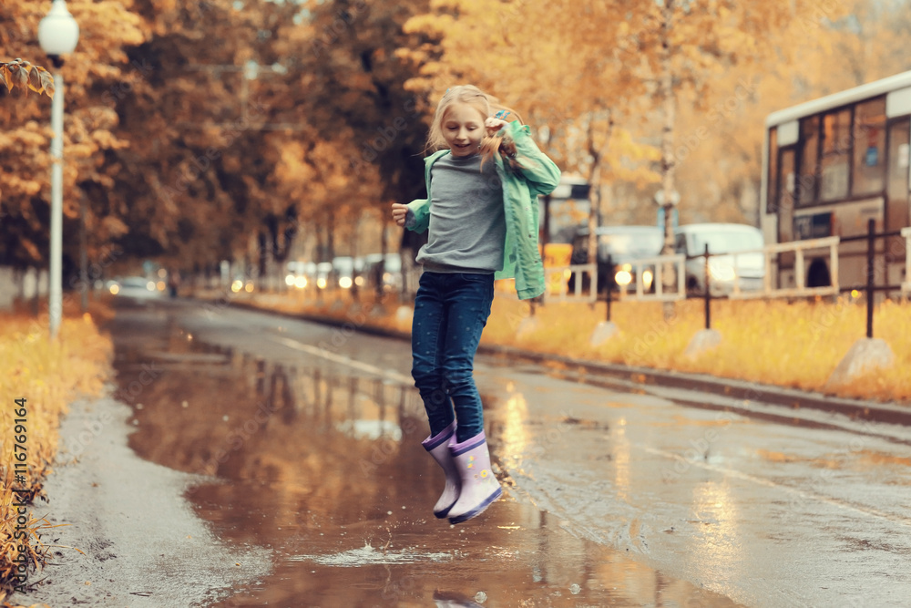 Fototapeta premium girl jumping in the puddles in the autumn rain