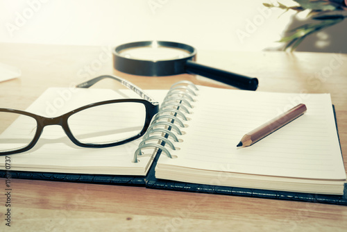 Open Blank notebook and pencil with magnifying glasses and