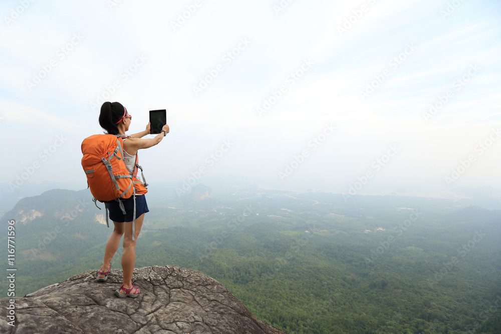 Obraz premium young woman backpacker taking photo on beautiful mountain peak