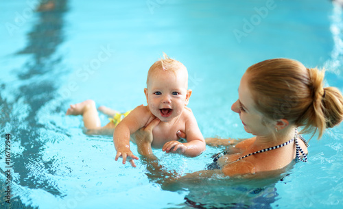 mother teaching baby swimming pool