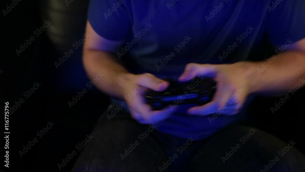 A man in his 20's intensely playing video games. A man in his 20's intensely playing video games.