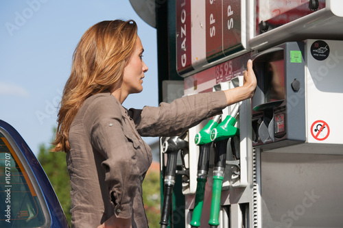 Fototapeta femme dans le doute à une pompe à essence
