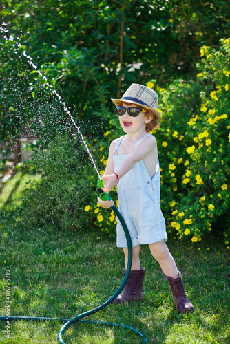 little boy watering the garden with hose