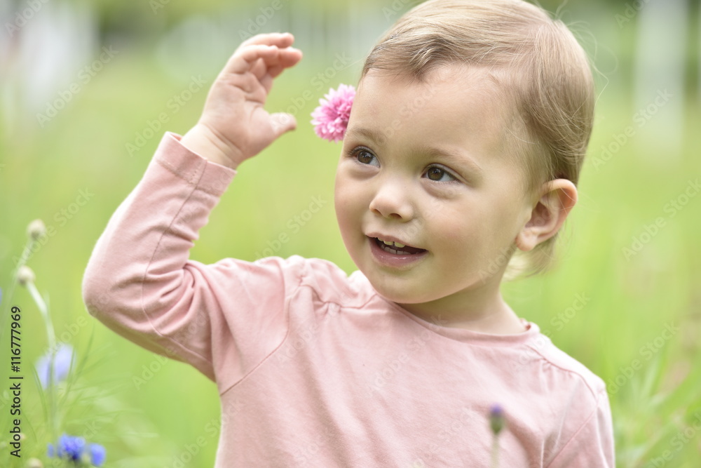 Cute 2-year-old girl playing in wild flower field Cute 2-year-old girl playing in wild flower field