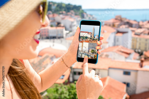 Young fwmale traveler photographing with smart phone Piran old town. Close up view focused on the phone screen photo