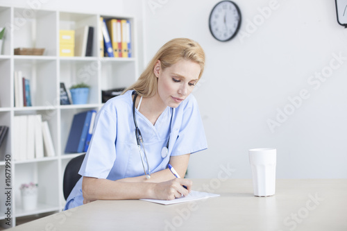 Young female doctor and practitioner working at desk 