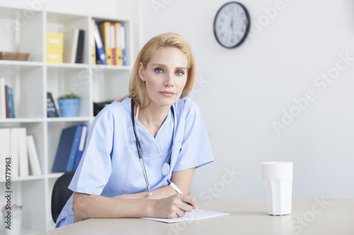 Young female doctor and practitioner working at desk 