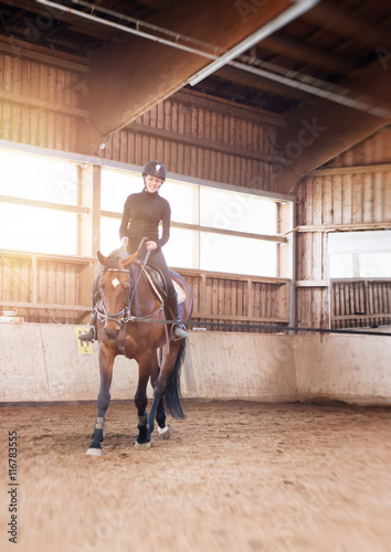 Young woman doing dressage practice with her horse