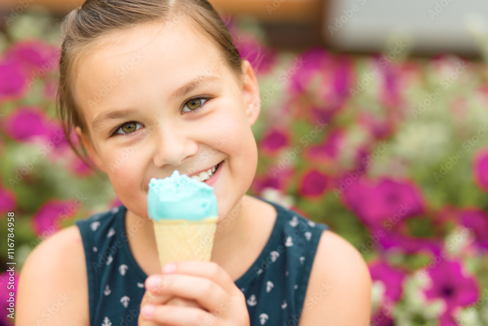 Little girl is eating ice-cream in park