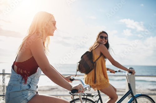 Two women going by bike on sunny day