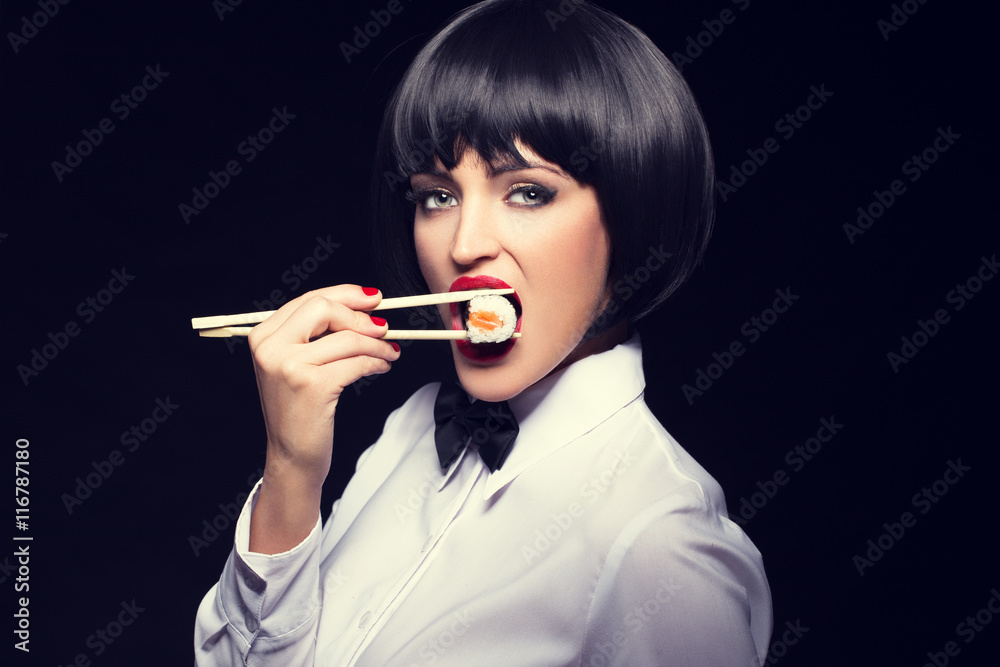 Sexy waiter eating sushi on black background