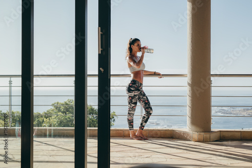 Fitness woman standing in the balcony and drinking water © Jacob Lund