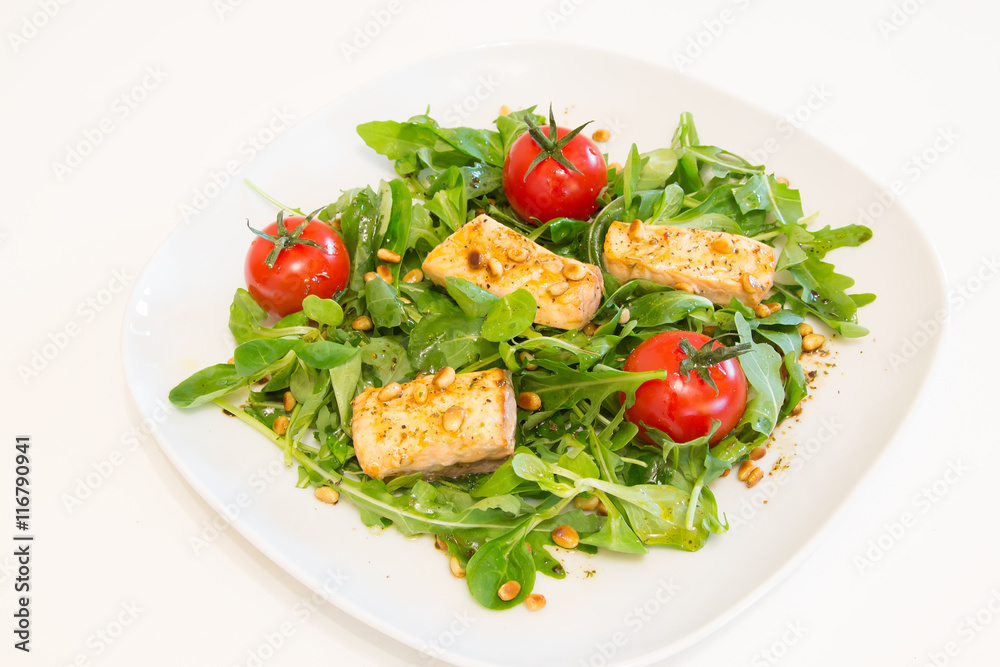 Salad with grilled salmon, green salad and pine nuts on a white plate Salad with grilled salmon, green salad and pine nuts on a white plate