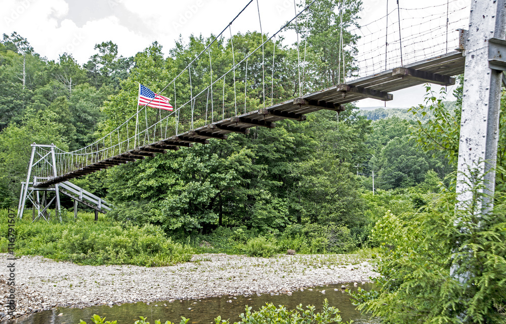 Obraz premium Swinging bridge crosses over a river.