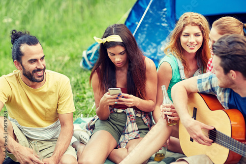 happy friends with drinks and guitar at camping