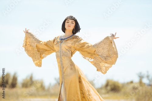Beautiful woman like Egyptian Queen Cleopatra on in desert outdoor.