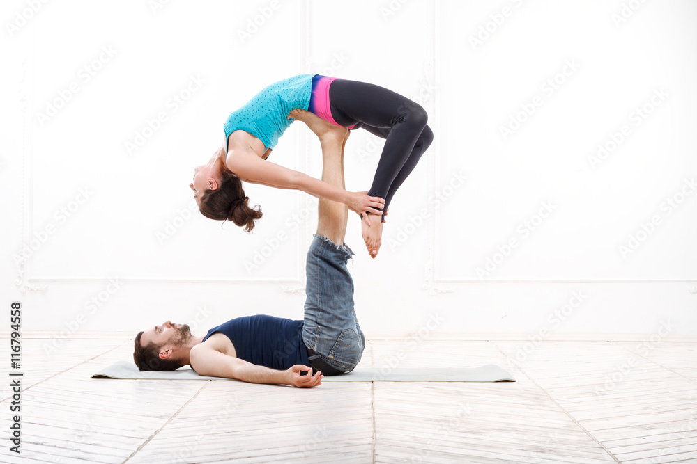 Beautiful Young Couple Practicing Acro-Yoga Beautiful Young Couple Practicing Acro-Yoga