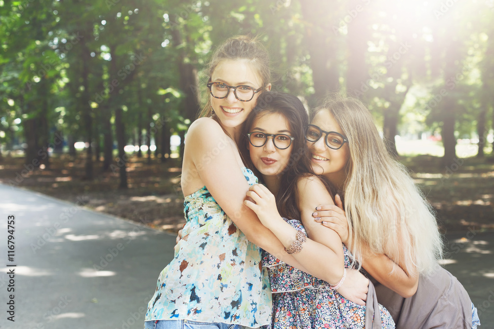 Fototapeta premium Three beautiful young boho chic stylish girls walking in park.