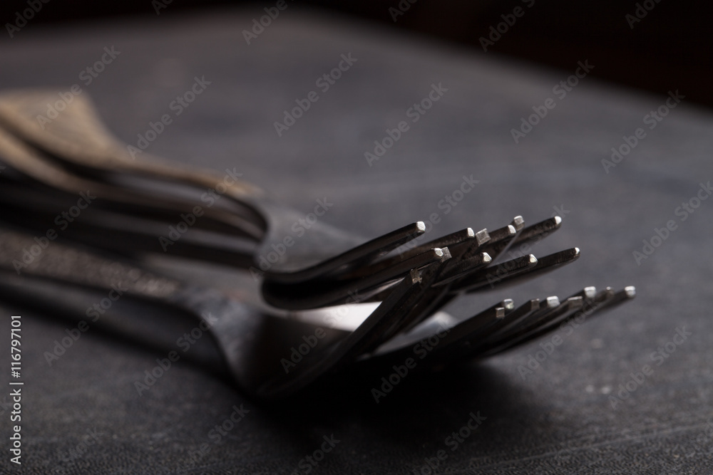 Lot of metal cutlery on a black background. Selective focus. Sha Lot of metal cutlery on a black background. Selective focus. Sha