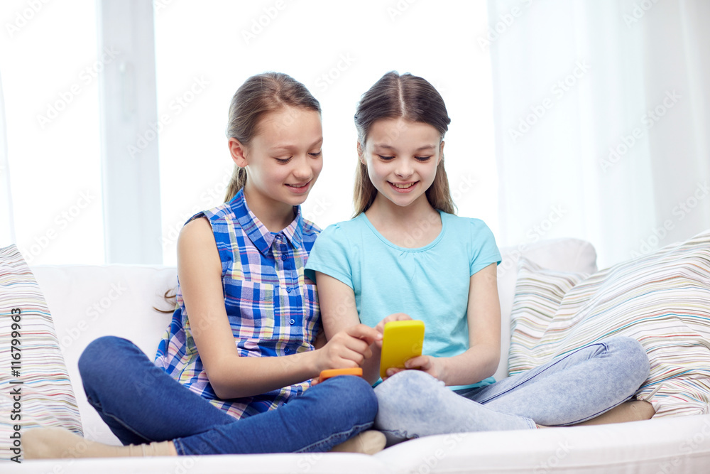 happy girls with smartphones sitting on sofa happy girls with smartphones sitting on sofa