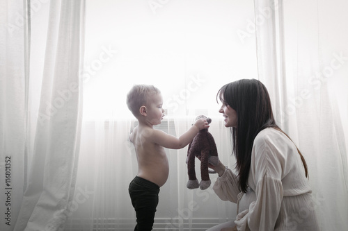 A heavily pregnant woman playing with her young son.