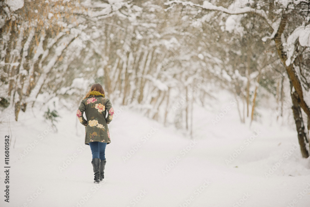 A woman walking in the snow in woodland. A woman walking in the snow in woodland.