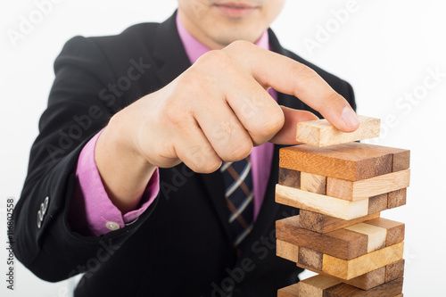 Business risk concept with businessman managing wood jenga 