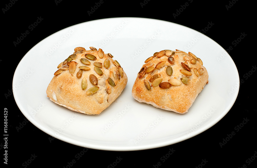 Two sandwich buns with pumpkin seeds on white plate Two sandwich buns with pumpkin seeds on white plate