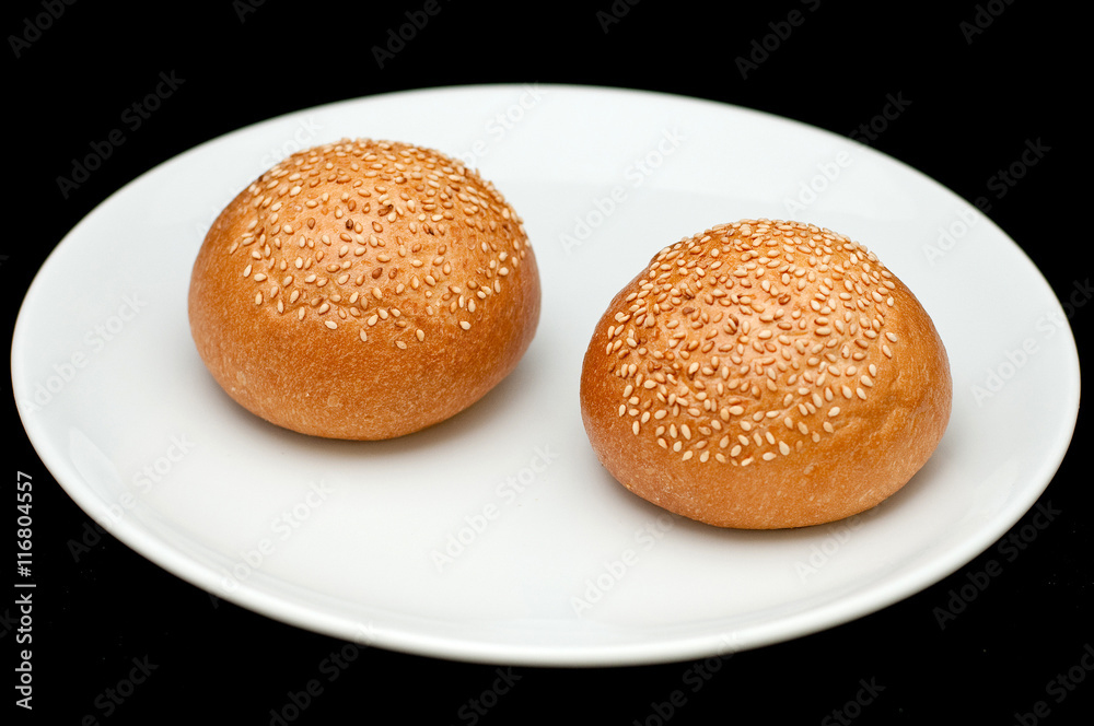 Two sandwich buns with sesame on white plate