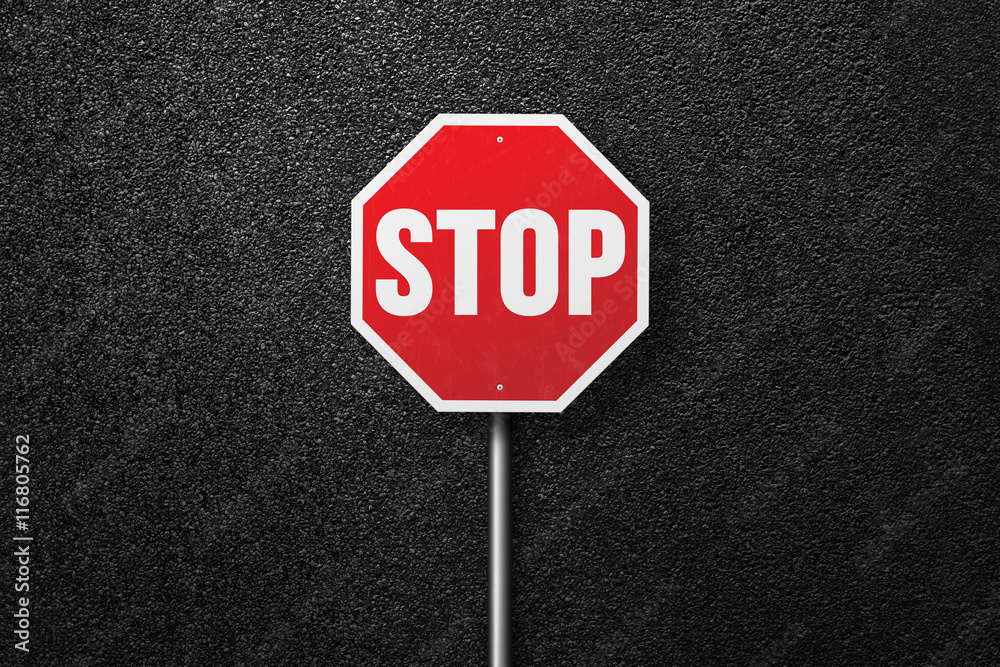 Red road sign with the words STOP on a background of asphalt. The texture of the tarmac, top view. Red road sign with the words STOP on a background of asphalt. The texture of the tarmac, top view.