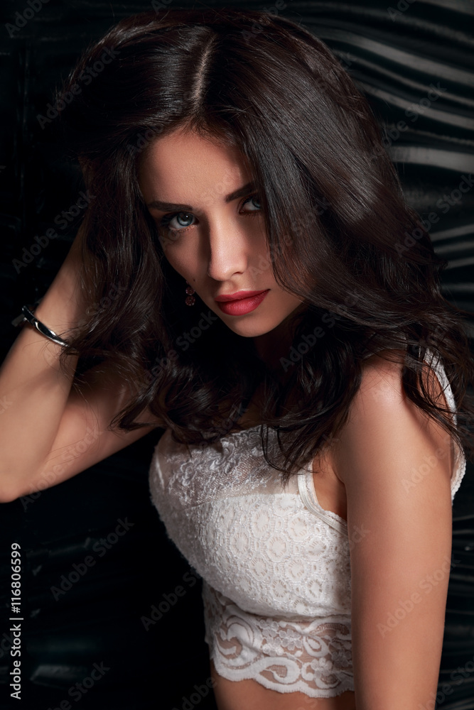 Seductive makeup brunette woman with long hair in white top posi Stock