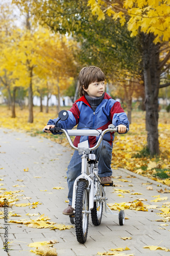 boy riding a bicycle in autumn park