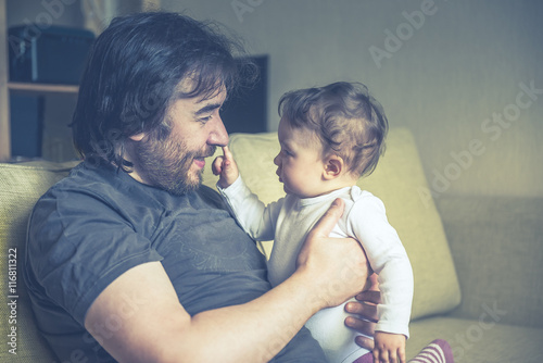 Happy father plays with his baby at home, vintage style photo photo