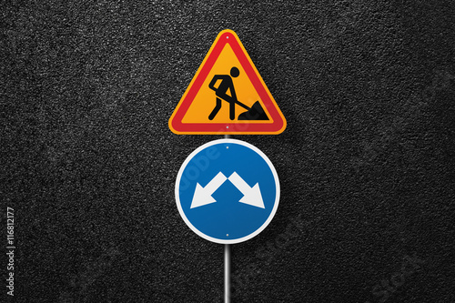 Road signs of the circular and triangular shape with a picture of a worker on a background of asphalt. Pointer. The texture of the tarmac, top view. © srzaitsev
