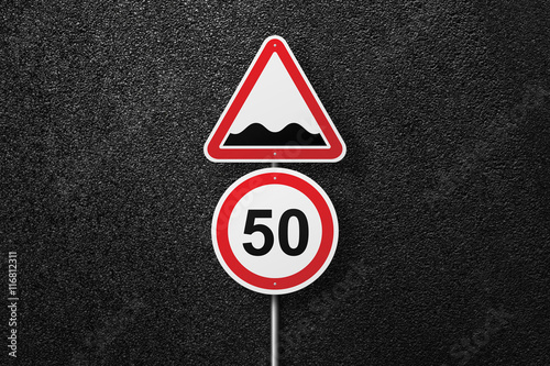 Road signs of the circular and triangular shape on a background of asphalt. Rough roads. Speed limit. The texture of the tarmac, top view.