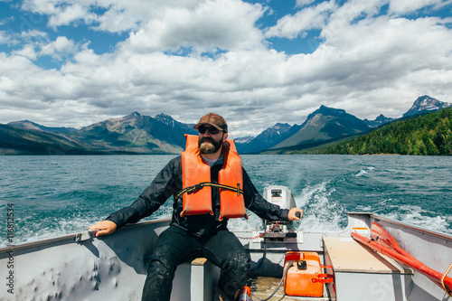 Man steering boat on Lake McDonald, Glacier National Park, Montana photo