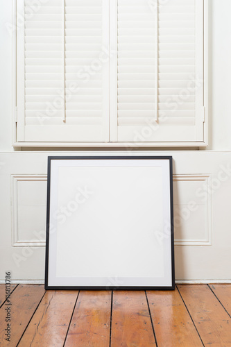 Black picture frame sitting on wooden floor