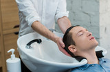 Profile view of a young man getting ready for his hair washed