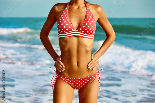 Sexy beautiful woman in creative red swimwear at the sea coast.