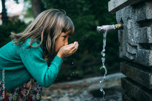 girl drinking water from a fountain photo