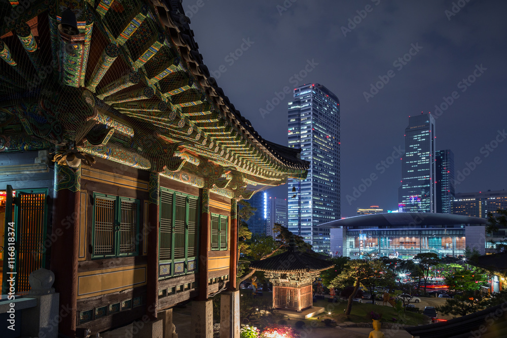 Fototapeta premium Ornate building at the Bongeunsa Temple and view of Gangnam in Seoul, South Korea at night.
