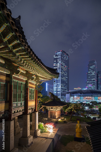 Ornate building at the Bongeunsa Temple and view of Gangnam in Seoul, South Korea at night.