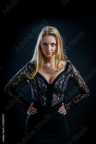 blonde girl on a black background in a dark guipure dress