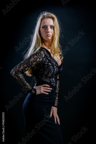 blonde girl on a black background in a dark guipure dress