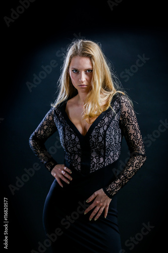 blonde girl on a black background in a dark guipure dress